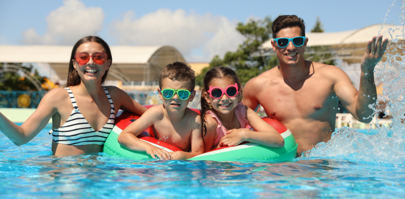 Family wearing colourful sunglasses together in a swimming pool