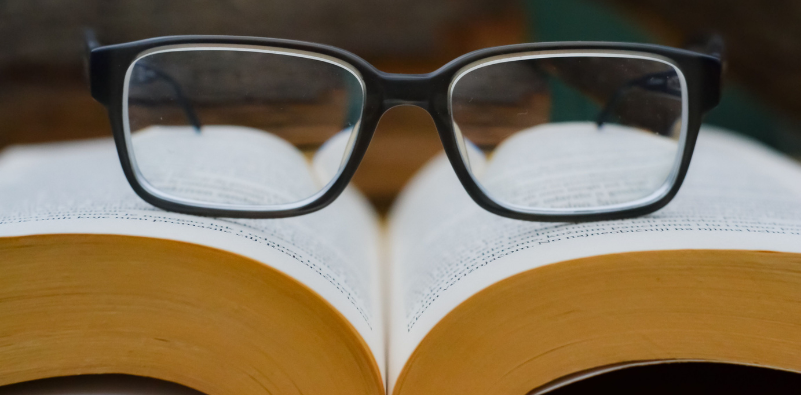 Pair of black reading glasses resting on an open book