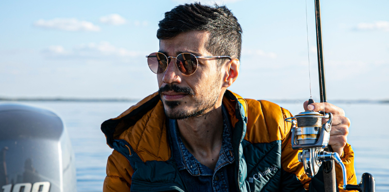 Man wearing sunglasses and holding a fishing rod on a boat
