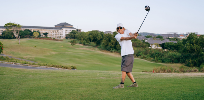 Golfer wearing sunglasses while taking a shot on the course