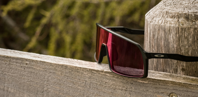 Oakley performance sunglasses resting on a wooden railing.
