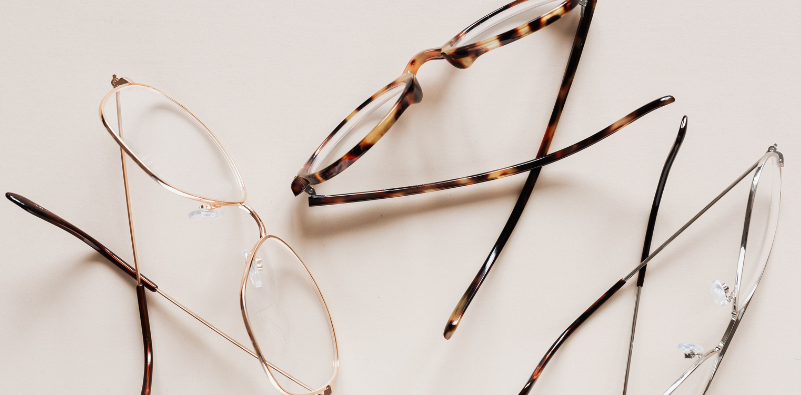 Three pairs of eyeglasses on a neutral surface in a range of colors and patterns.