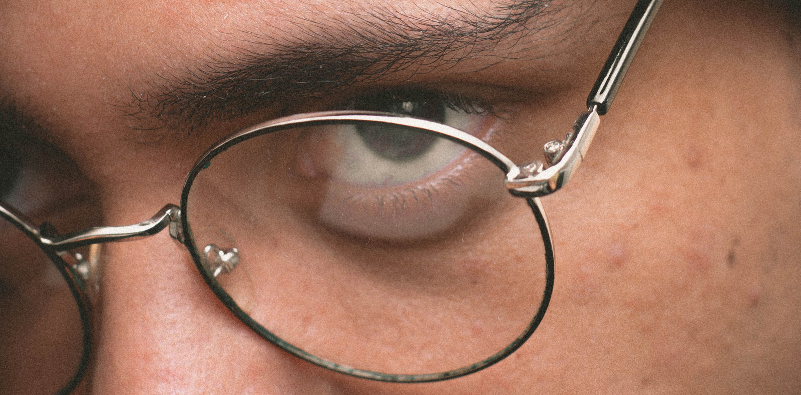 Close-up of a person’s eye behind thin, round metal glasses